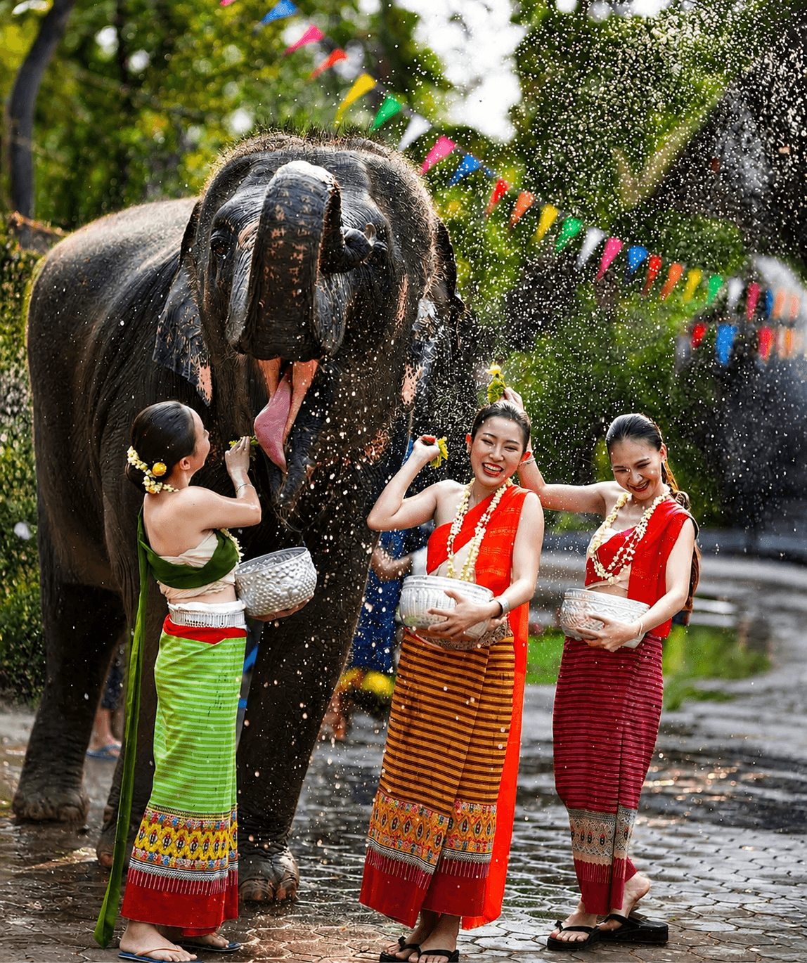 Elephant enjoying a festive water celebration with traditionally dressed guests