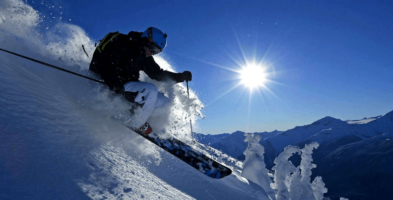 Skier descending a sunlit snowy slope at Auli